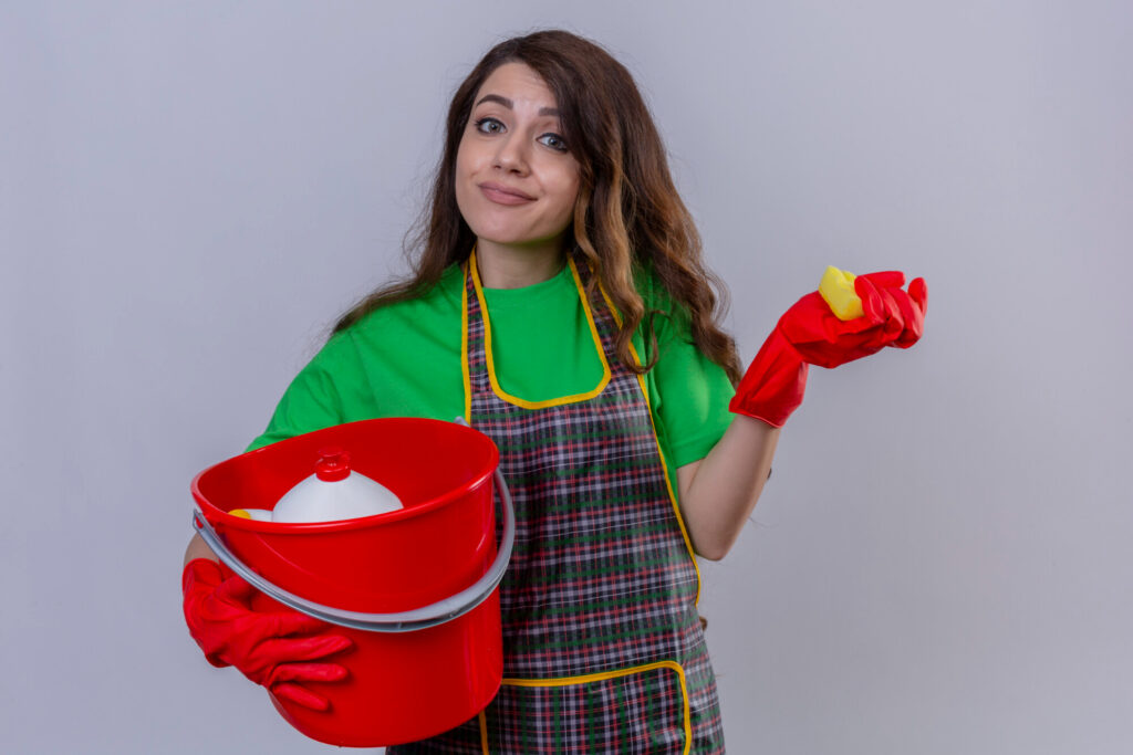 essoa sorrindo enquanto usa luvas para limpar o vaso sanitário com produtos adequados, mostrando higiene e eficácia