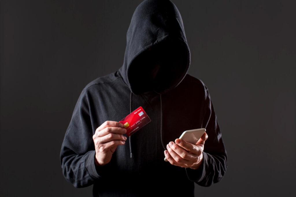 Pessoa lendo uma mensagem de texto em um celular com símbolos de alerta, representando os novos golpes por SMS.