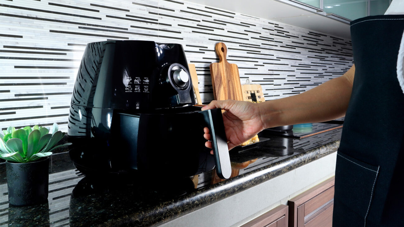 Mãos de um adulto preparando vegetais coloridos para um lanche saudável, mostrando a simplicidade da culinária na air fryer.