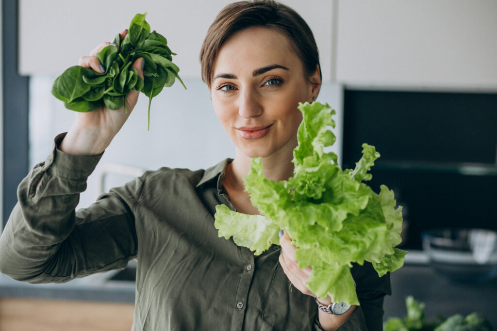 Mãos secando folhas de alface com uma centrífuga de salada, um passo essencial para a correta conservação de alimentos.