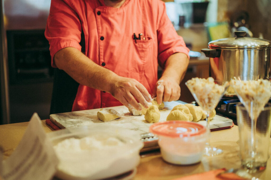 Mãos de um confeiteiro abrindo uma massa na bancada, revelando o segredo para massas leves