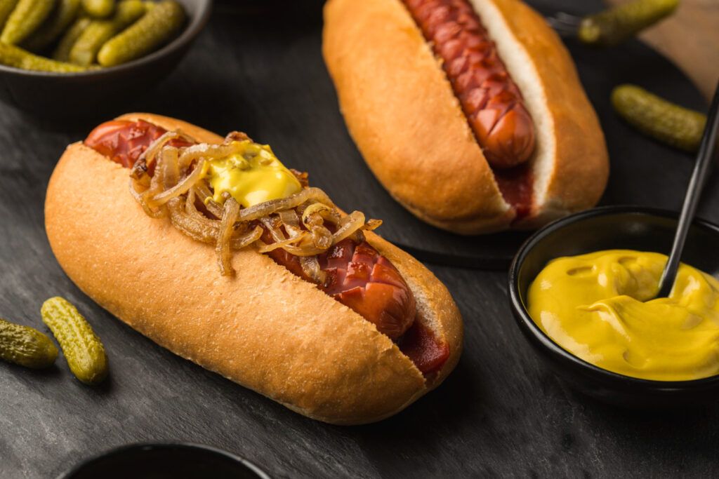 Close-up de salsichas boiando em uma panela com água fervente, ilustrando o hábito de ferver a salsicha.