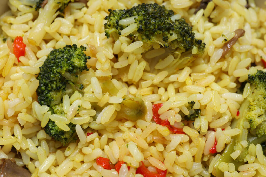 Copo medidor despejando arroz cru dentro de uma panela de arroz elétrica antes do cozimento