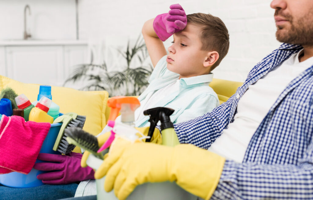 Frascos de produtos de limpeza seguros, como vinagre e bicarbonato, ao lado de uma esponja em uma bancada